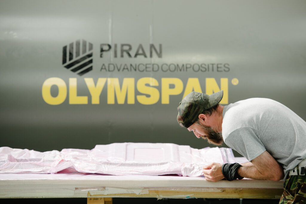 Member of the Piran team in cap and grey t-shirt working on a purple sheet material