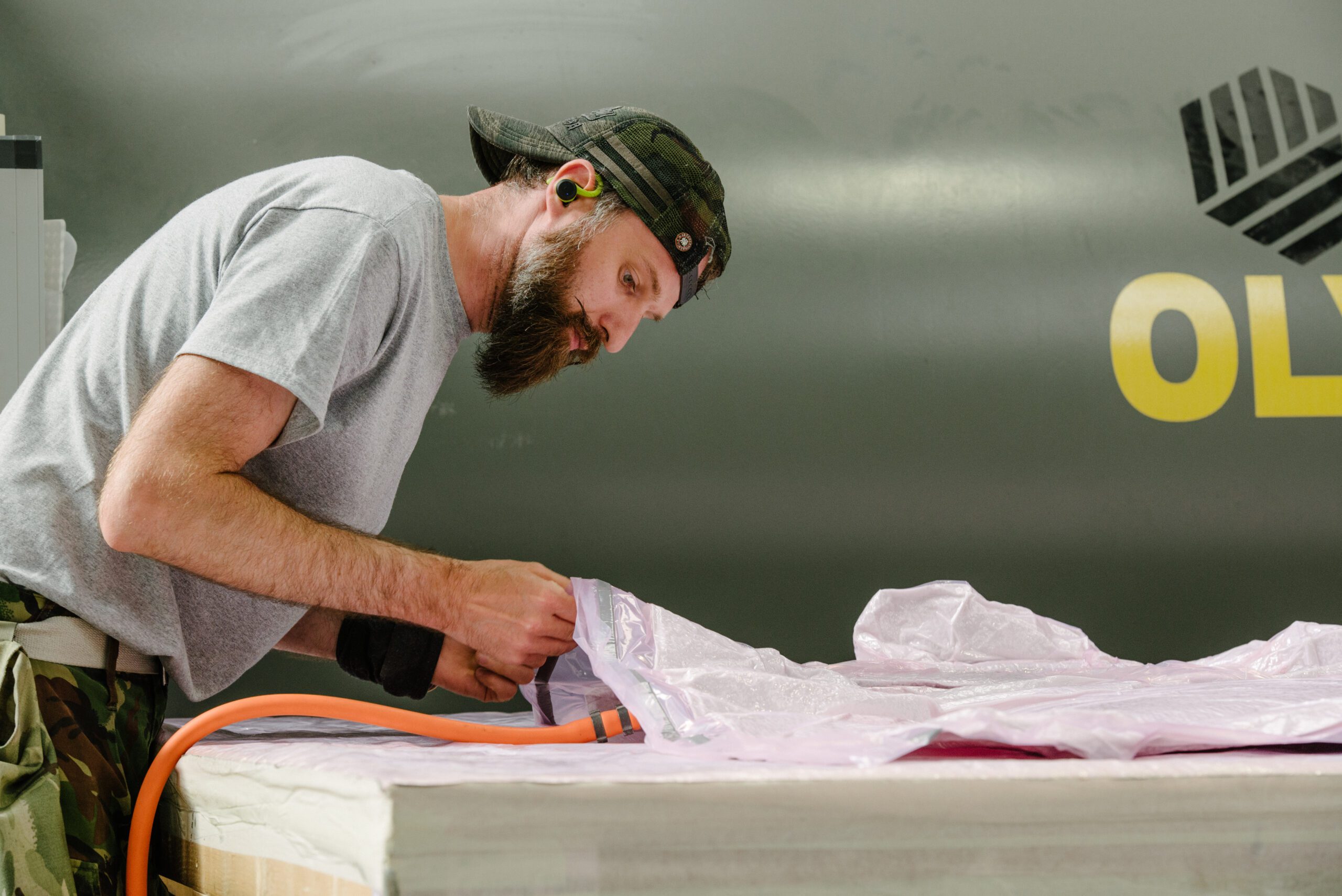 Member of the Piran team in cap and grey t-shirt working on a purple sheet material