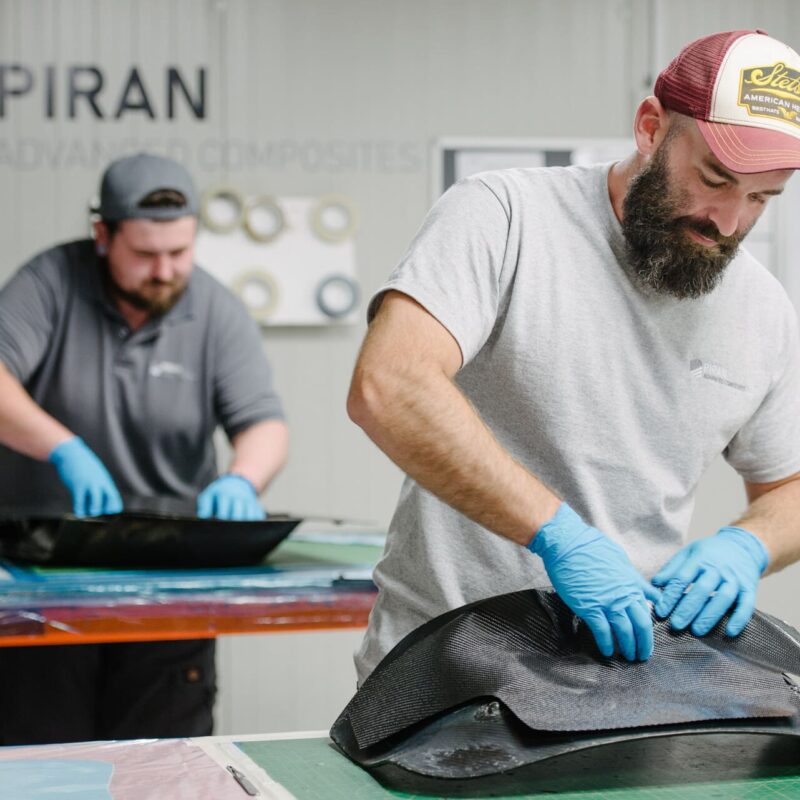 Two men working by hand on carbon fibre parts